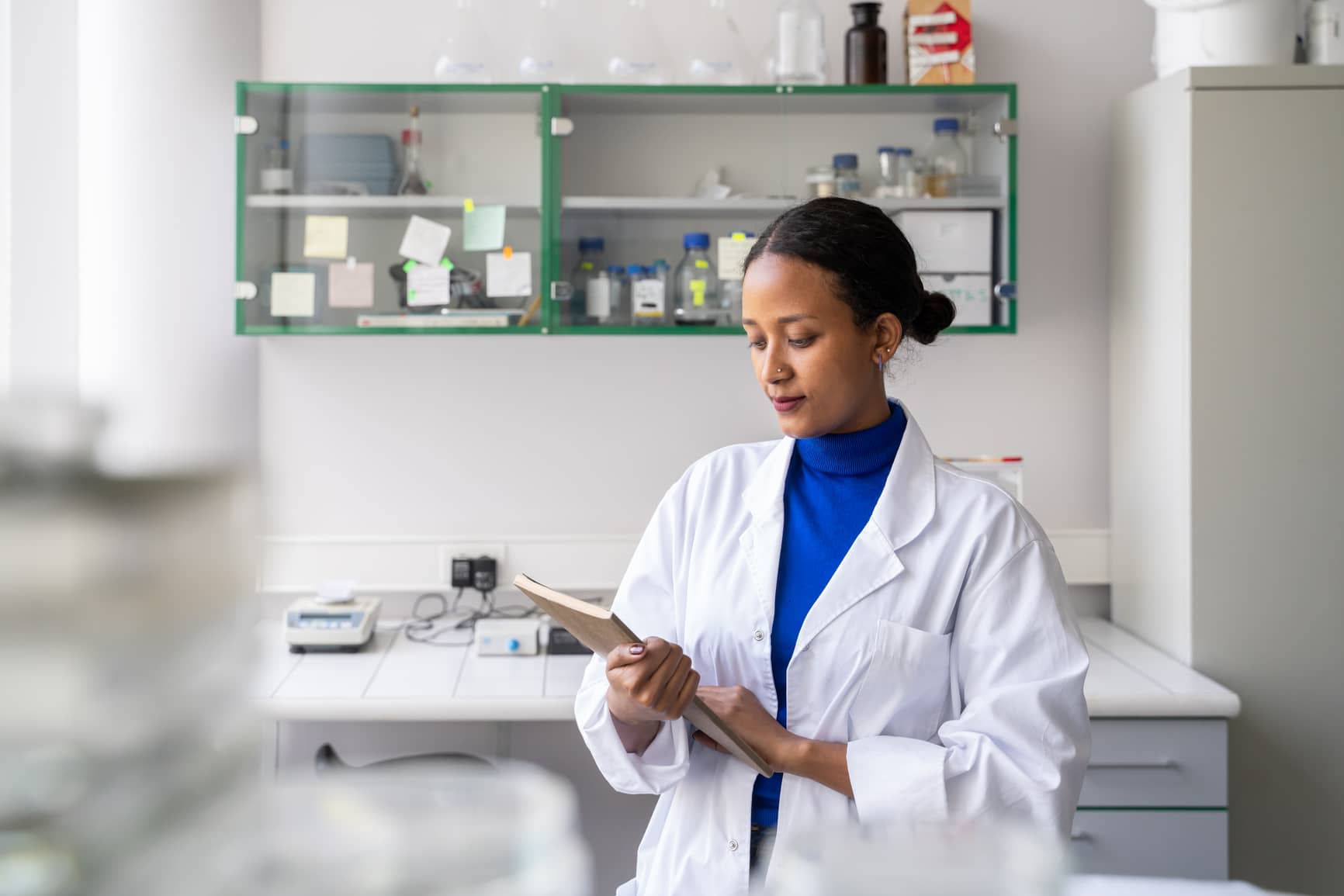 Scientist holding notebook in modern lab.